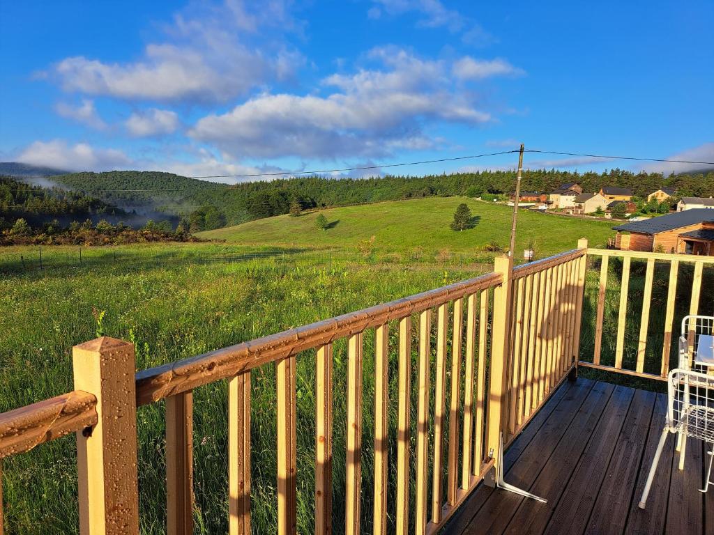 une terrasse avec une chaise et une vue sur un champ dans l'établissement Chalet en bois tout confort, à Valleraugue