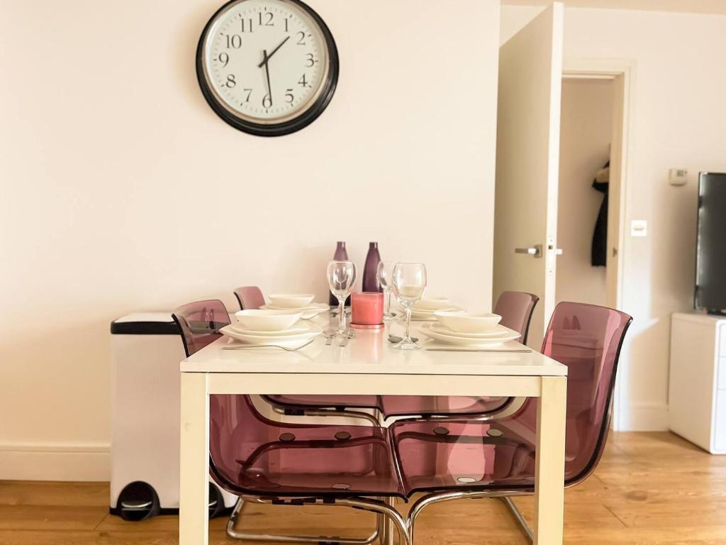 mesa de comedor con sillas y reloj en la pared en Omega Terrace, Luxury Modern Interior, Located Close To Alexandra Palace en Londres
