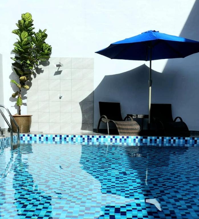 a swimming pool with an umbrella and two chairs and a table at 2Houses with A Huge Private Pool 8 Bedrooms & 8 Bathrooms in Kuah