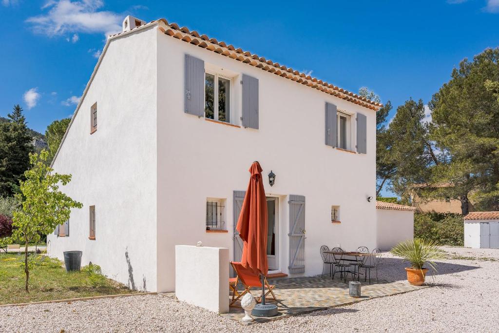 une maison blanche avec un parasol orange devant elle dans l'établissement Rez-de-villa à 15 minutes de Cassis, à Roquefort-la-Bédoule