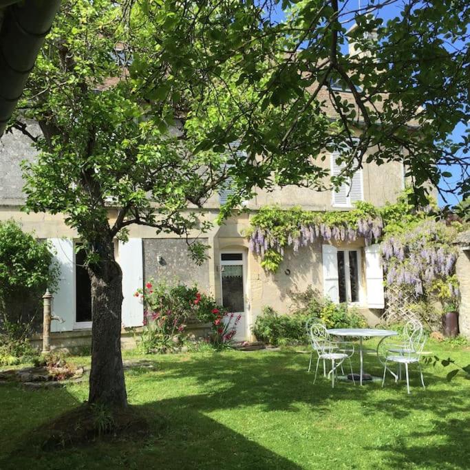 une maison avec une table et des chaises dans la cour dans l'établissement Maison de campagne à la mer, à Ver-sur-Mer