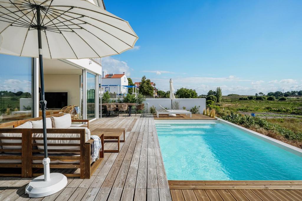 a house with a swimming pool and an umbrella at Villa Possanco, Comporta beach villa in Comporta