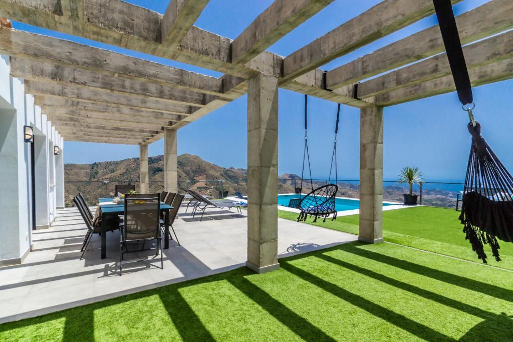 un patio con mesa, sillas y un columpio en Recently built Holiday Home El Limonar, en La Herradura