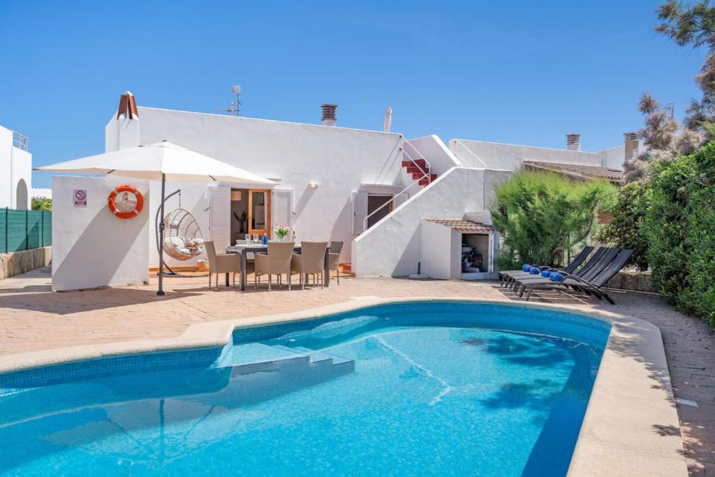 una piscina di fronte a una casa con ombrellone di Villa Ido a Cala'n Bosch