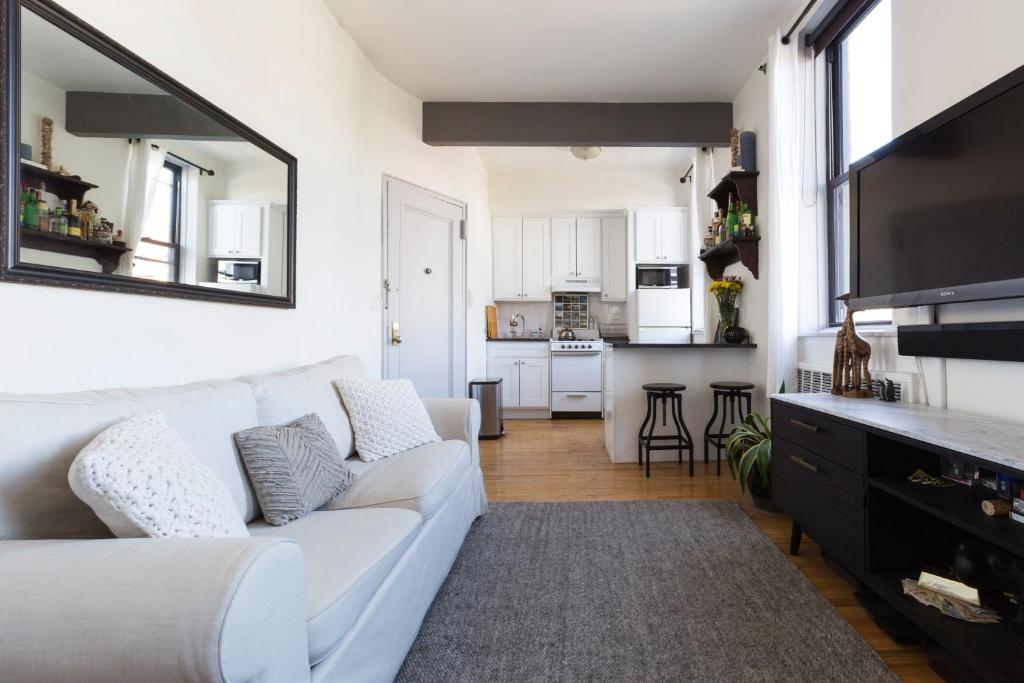 a living room with a white couch and a kitchen at Sunny Stylish West Village Condo in New York