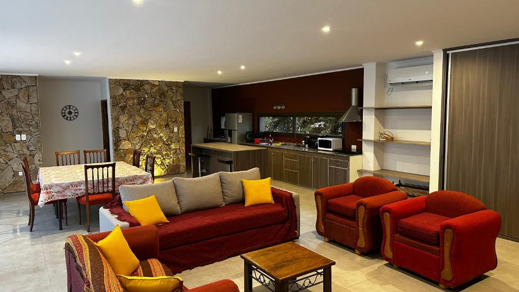 a living room with a couch and chairs and a kitchen at Chacras House in Chacras de Coria