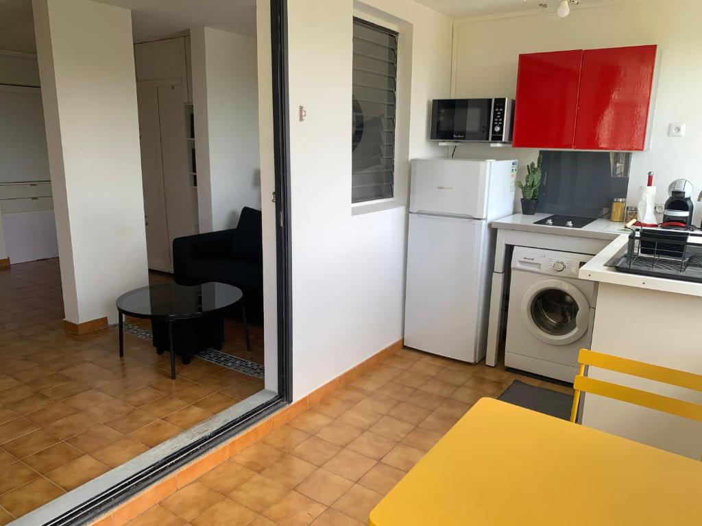 a small kitchen with a white refrigerator and a table at Bel appartement situé idéalement in Schœlcher