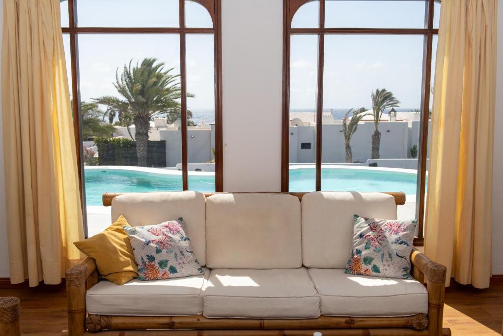 ein weißes Sofa im Wohnzimmer mit Fenstern in der Unterkunft Villa Blanca Nudist Exclusive in Charco del Palo