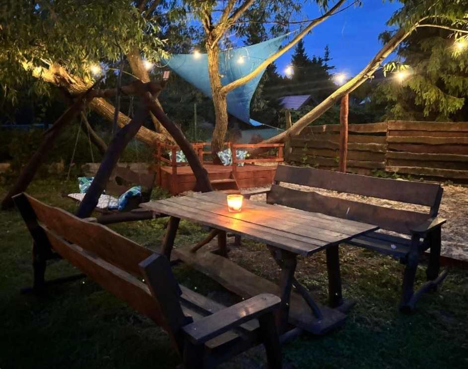 a wooden picnic table with a candle sitting next to two benches at Jagodzianka in Miłki