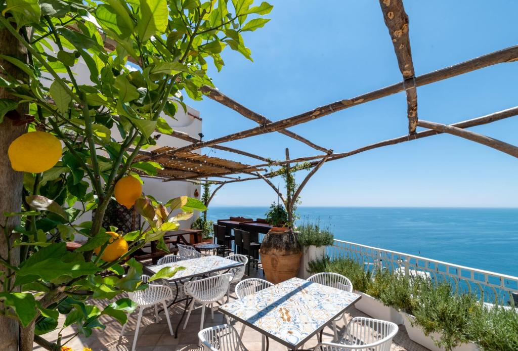 a patio with tables and chairs and a view of the ocean at Hostel Brikette in Positano