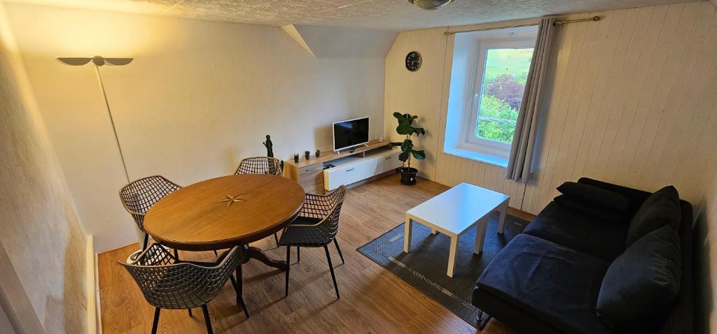 ein Wohnzimmer mit einem Tisch und einem Sofa in der Unterkunft L'appart - Couvet in Couvet