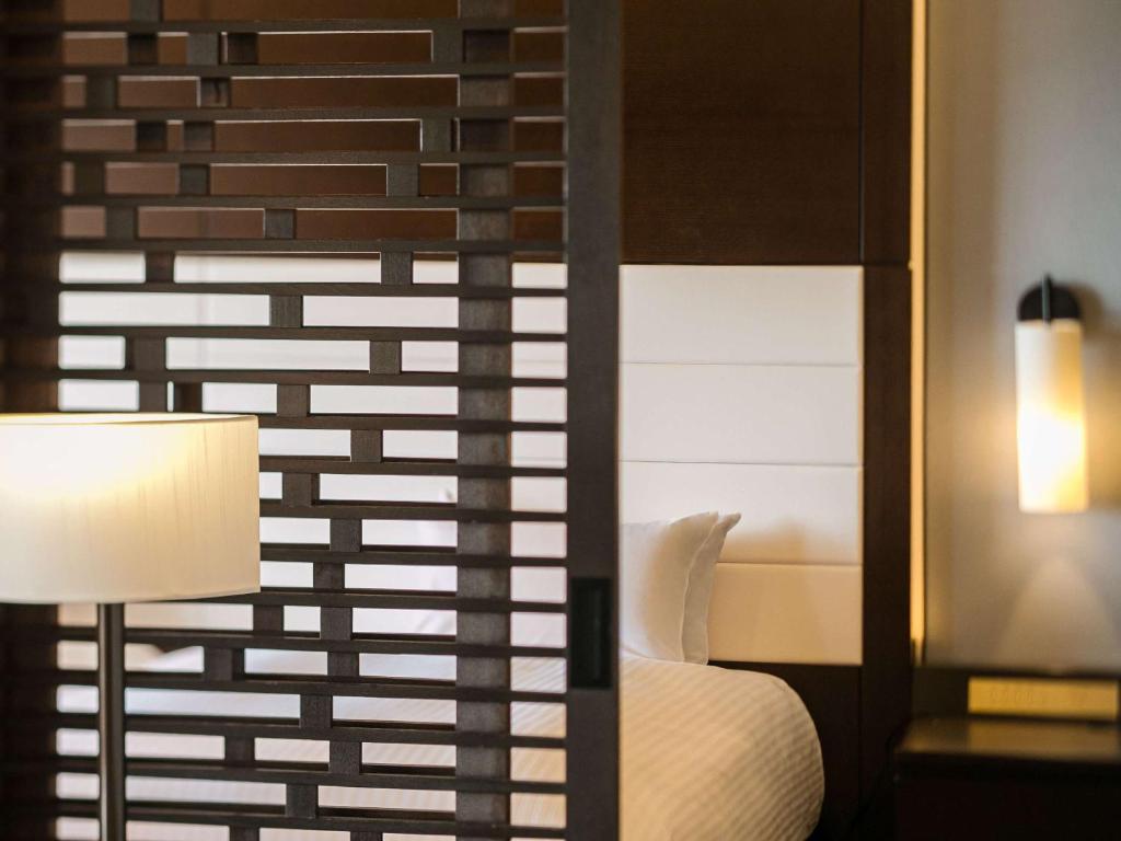 a bedroom with a bed and a lamp and a mirror at Grand Mercure Okinawa Cape Zanpa Resort in Yomitan