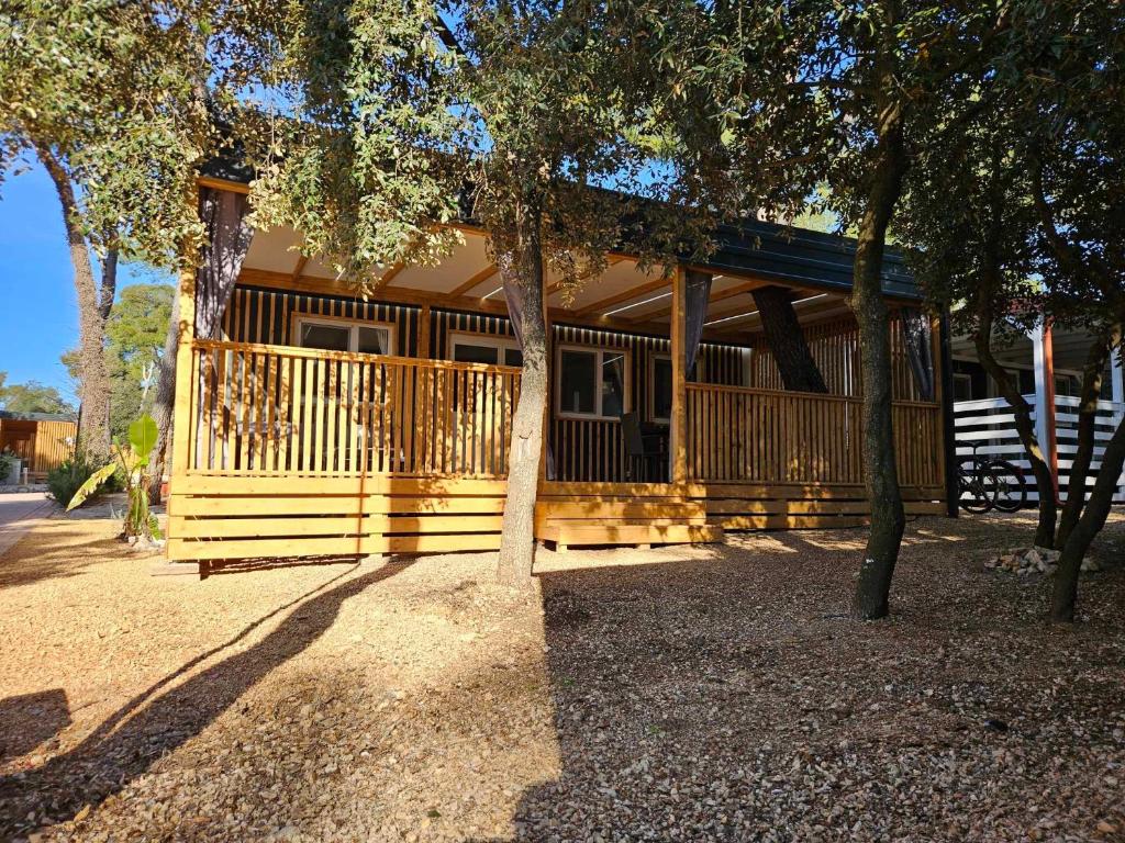 een huis met een veranda met een boom bij Paradiso mobile home in Biograd na Moru