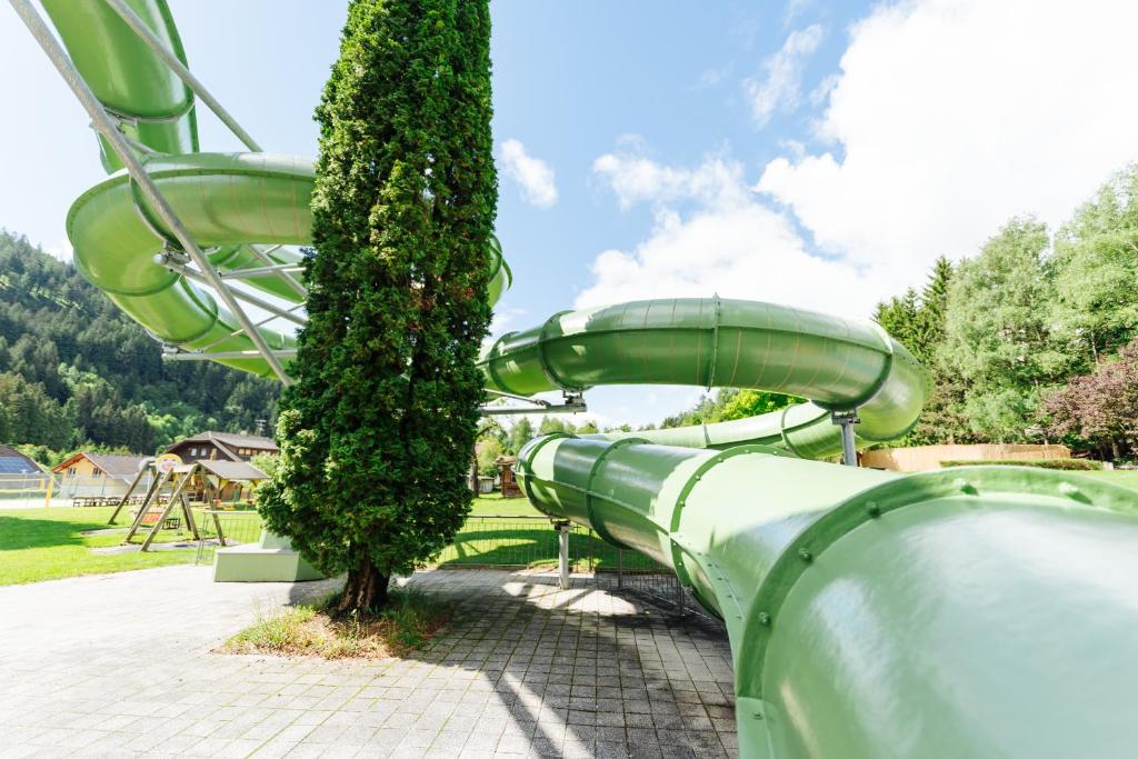 a green slide in a park with a tree at Familienhotel Trebesingerhof in Trebesing