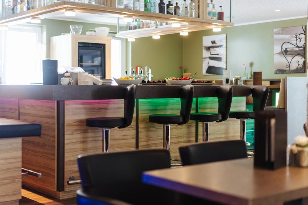 a restaurant with a bar with black chairs at Familienhotel Trebesingerhof in Trebesing