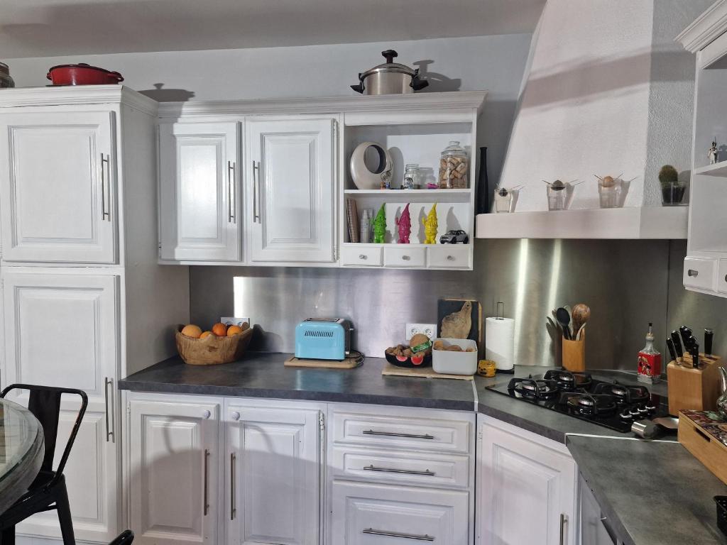 une cuisine avec des armoires blanches et un comptoir dans l'établissement La maison du bonheur, à Caumont-sur-Durance