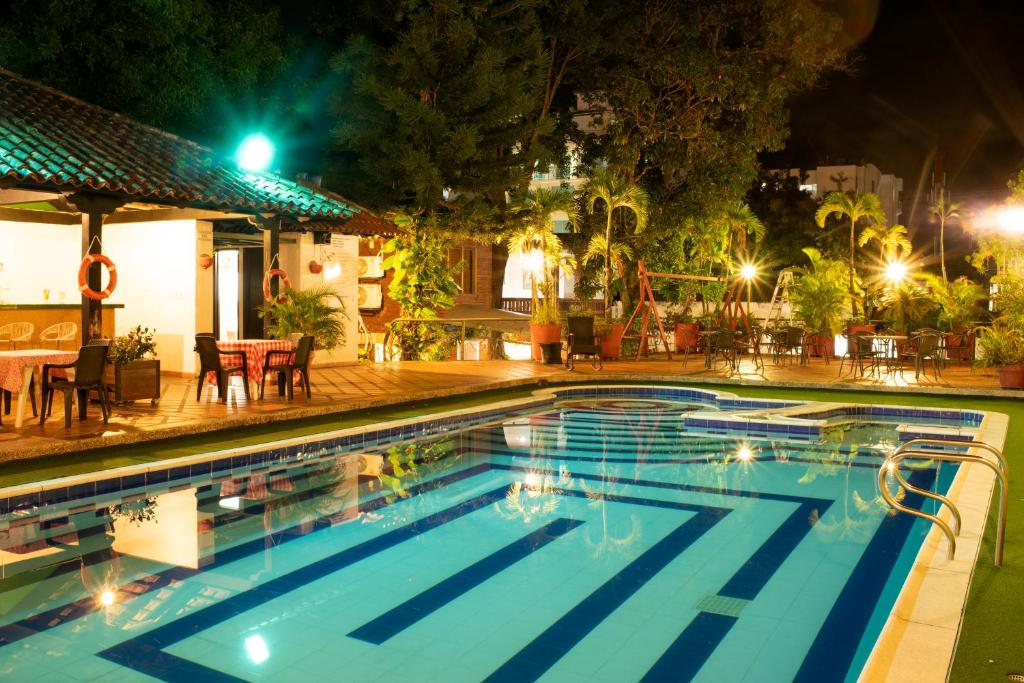 a swimming pool at night with a table and chairs at Hotel Camoruco in Yopal