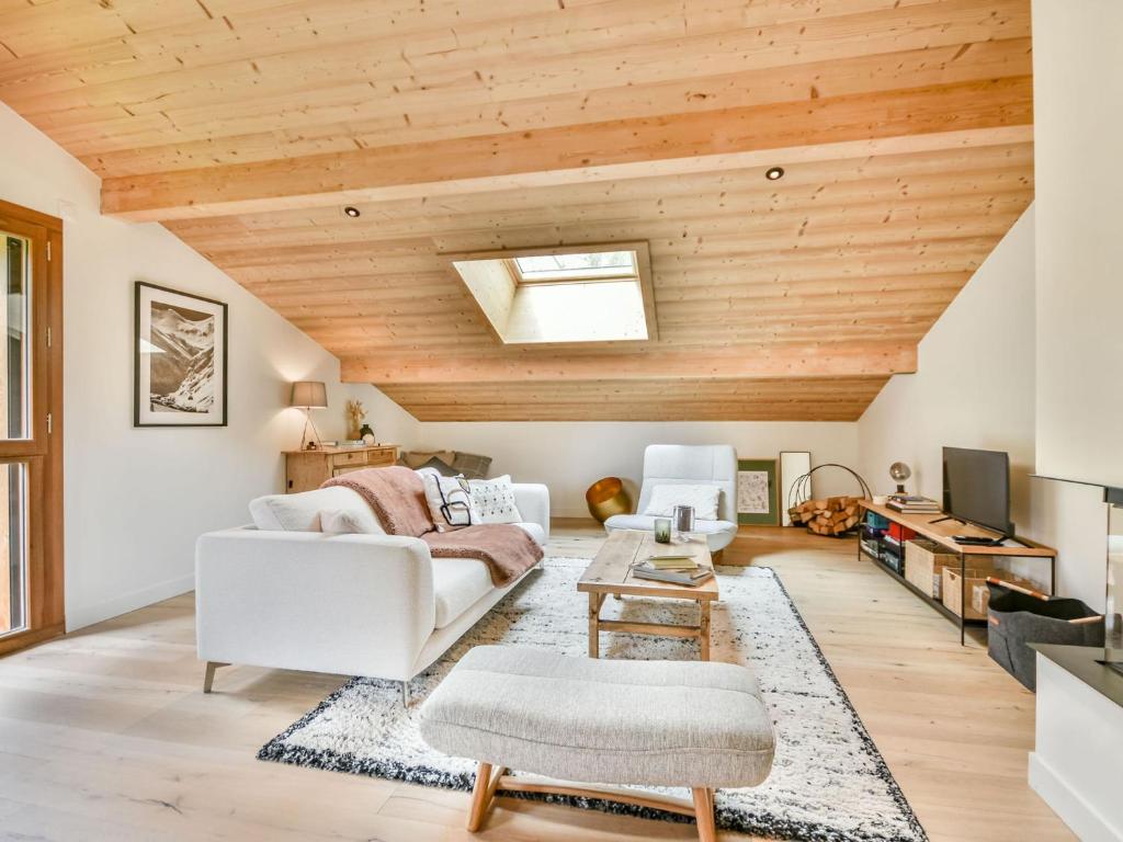 Elle comprend un salon doté d'un mobilier blanc et de plafonds en bois. dans l'établissement Appartement T3 Neuf aux Gets - Près des Pistes, 2 Parkings + Box, Linge Inclus - FR-1-685-71, aux Gets