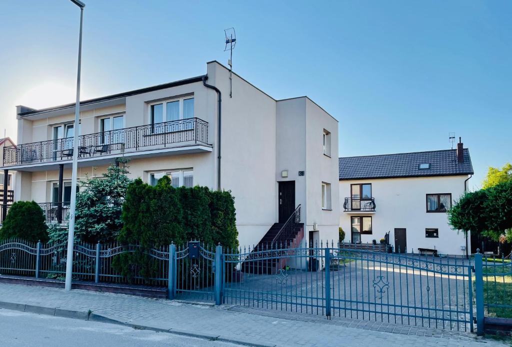 een wit huis met een blauw hek ervoor bij Apartament Leona in Ostrowo