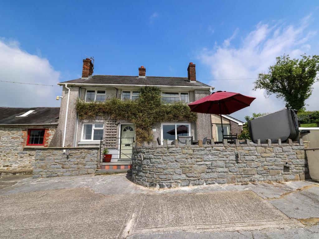 una casa con una pared de piedra y una sombrilla en Aberdauddwr en Llanwnen