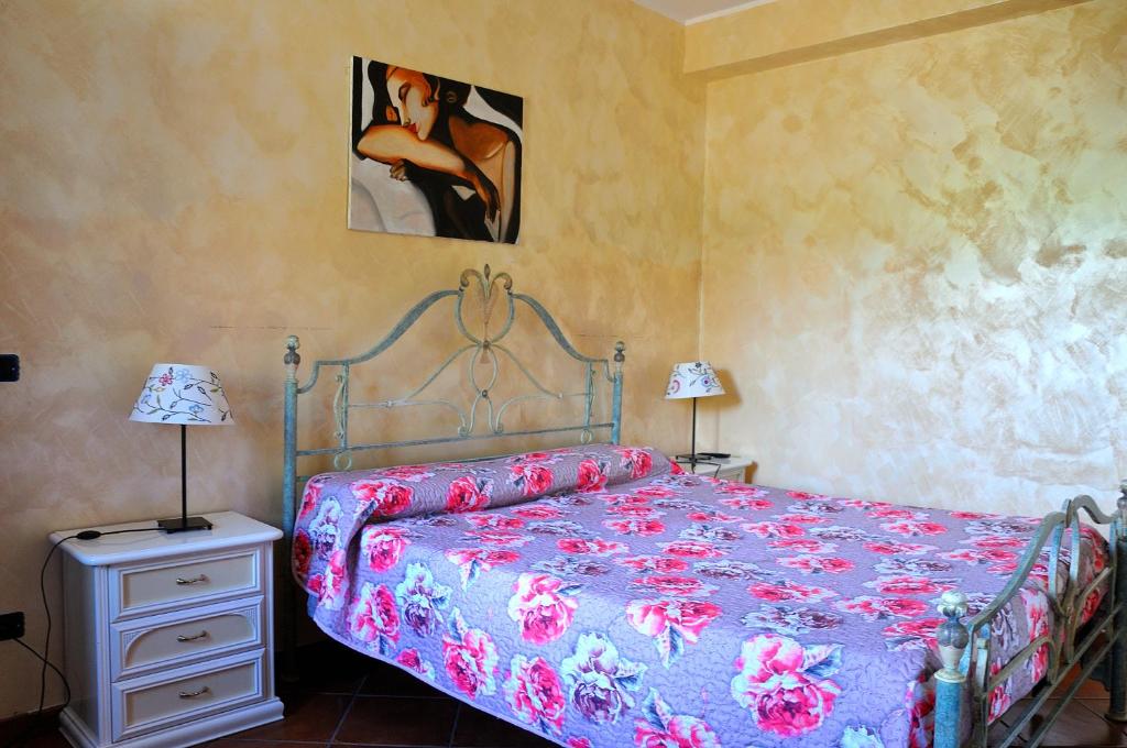 ein Schlafzimmer mit einem Bett, zwei Lampen und einem Gemälde in der Unterkunft B&B Colle Mattia in Colonna