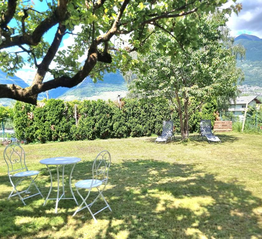 two chairs and a table in a yard with a tree at MARY HOUSE @ in Sondrio