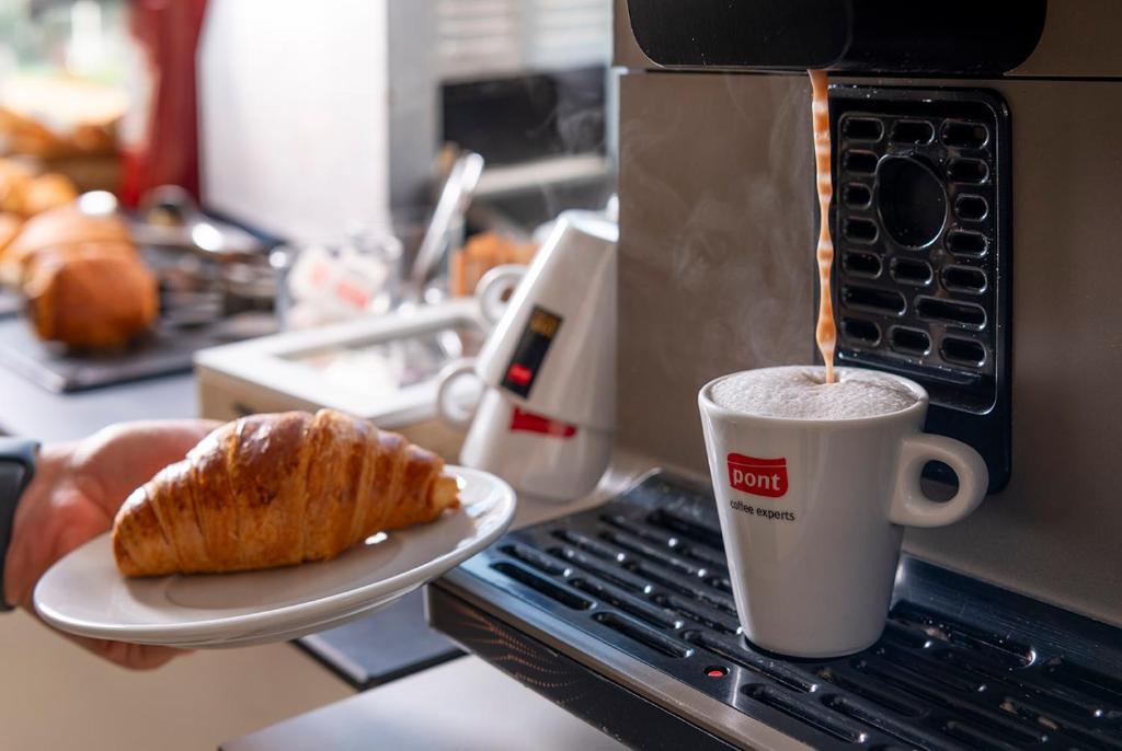 a cup of coffee and a plate with a pastry at Apartaments Els Llorers in Lloret de Mar