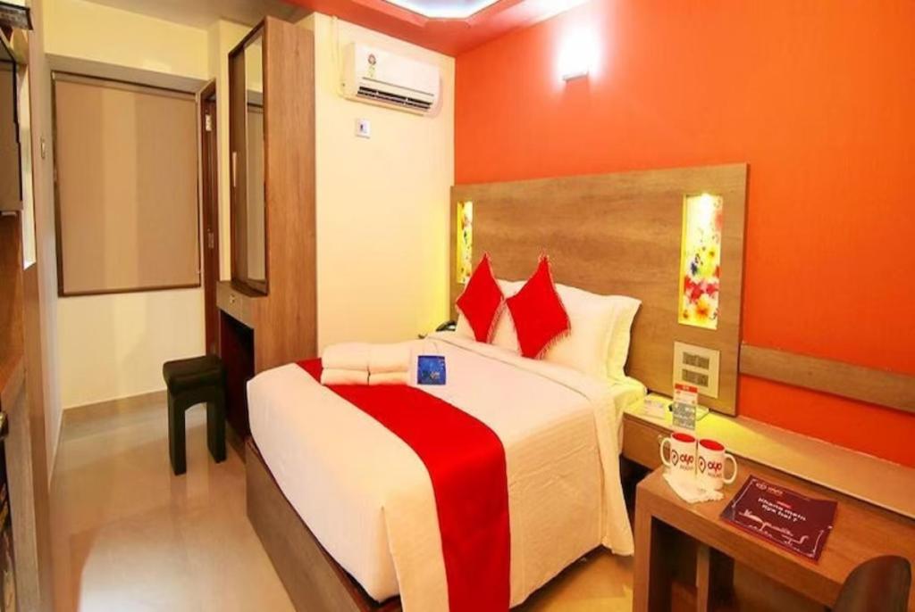 Hotel New Ashiyana Palace Varanasi Near Railway Station 400m في فاراناسي: غرفة نوم بسرير كبير وبجدران حمراء ومكتب