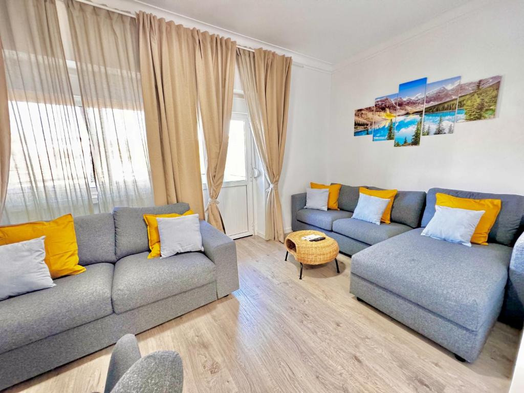 ein Wohnzimmer mit einem grauen Sofa und gelben Kissen in der Unterkunft Caparica Villa blue beach in Costa da Caparica