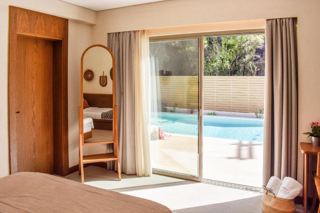 a bedroom with a view of a swimming pool at Mandraki Village Boutique Hotel in Koukounaries