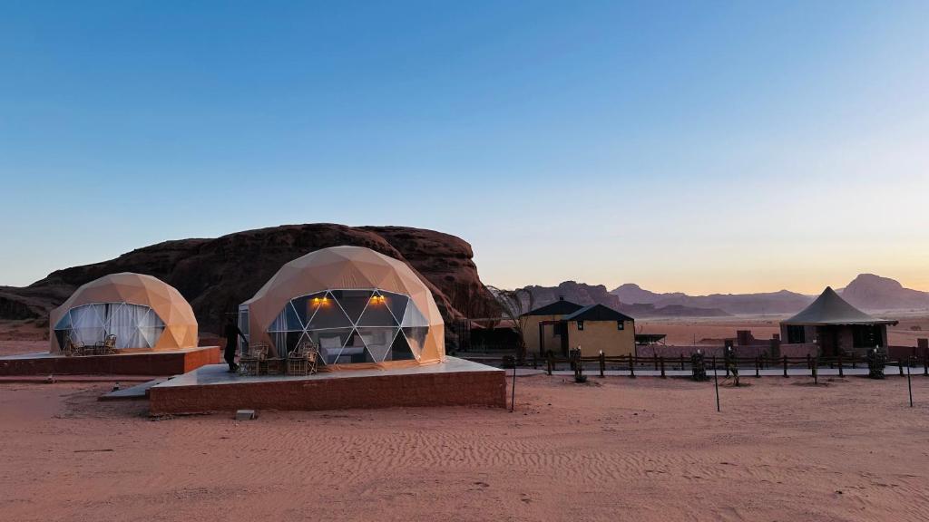 a group of domes in a desert with a mountain at wadi rum fox road camp & jeep tour in Wadi Rum