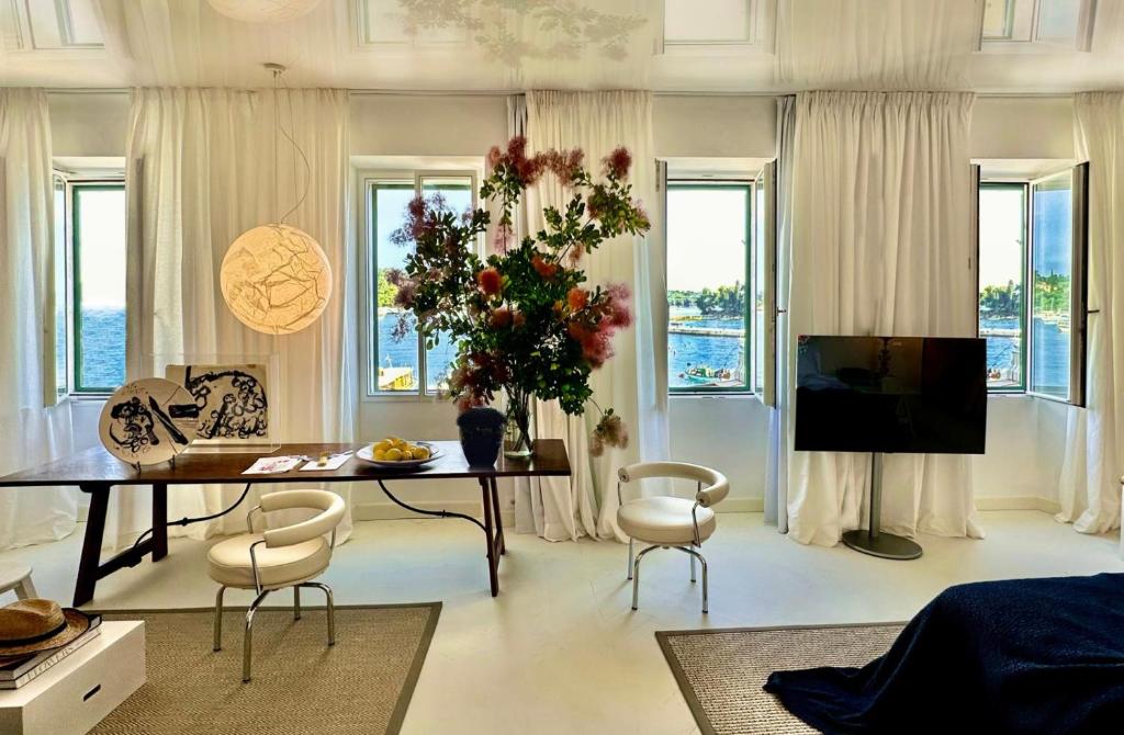 Una sala de estar con una mesa y sillas y un televisor. en Apollo Suite Rovinj, en Rovinj