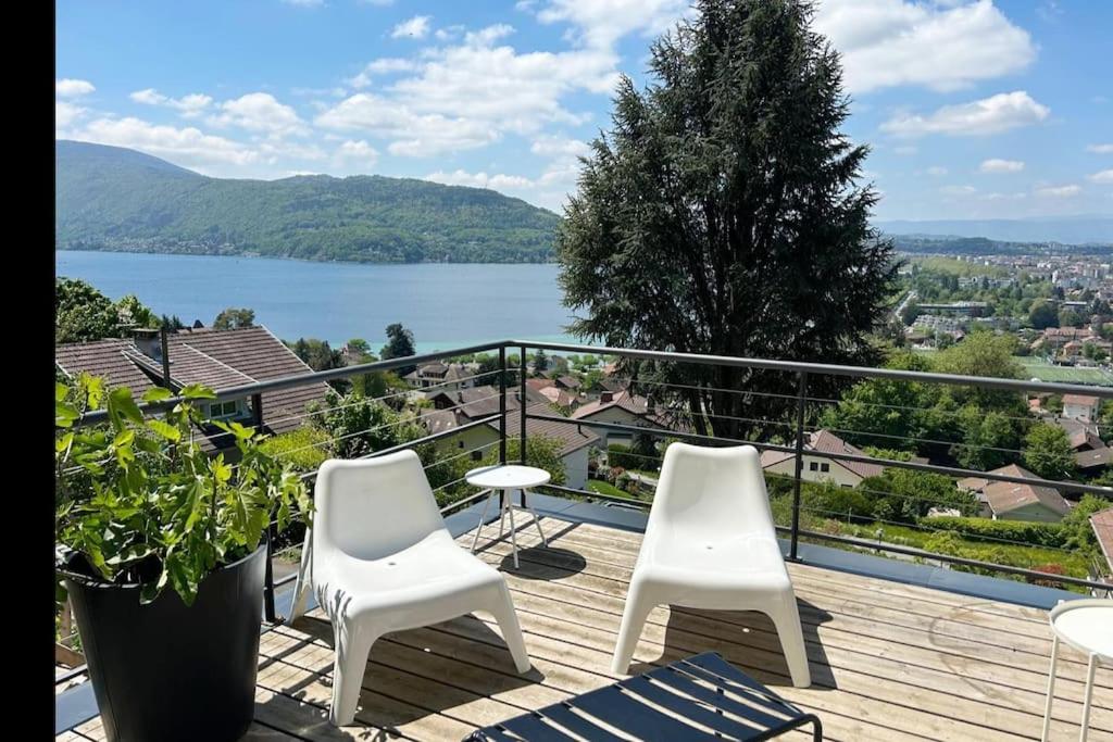 un balcon avec des chaises blanches et une vue sur un lac dans l'établissement Grand appartement T4, vue unique lac, terrasse et spa, à Annecy-le-Vieux