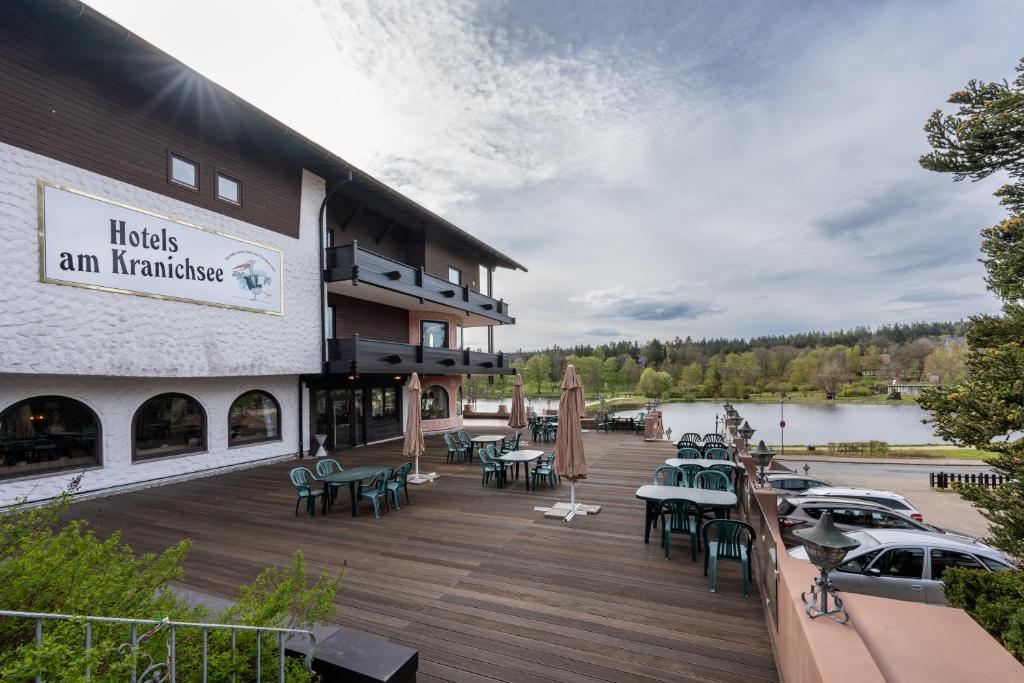 un restaurante con mesas y sillas en una terraza de madera en Hotels am Kranichsee, en Hahnenklee-Bockswiese