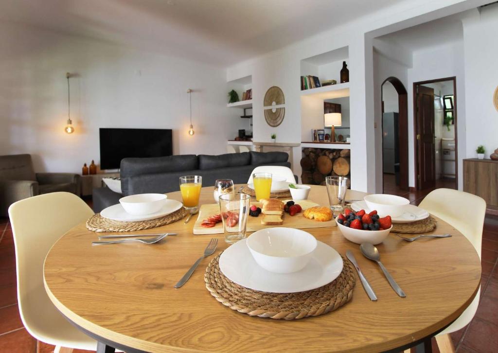 a wooden table with plates and bowls of food on it at Casa do Altinho in Vila Nova de Milfontes