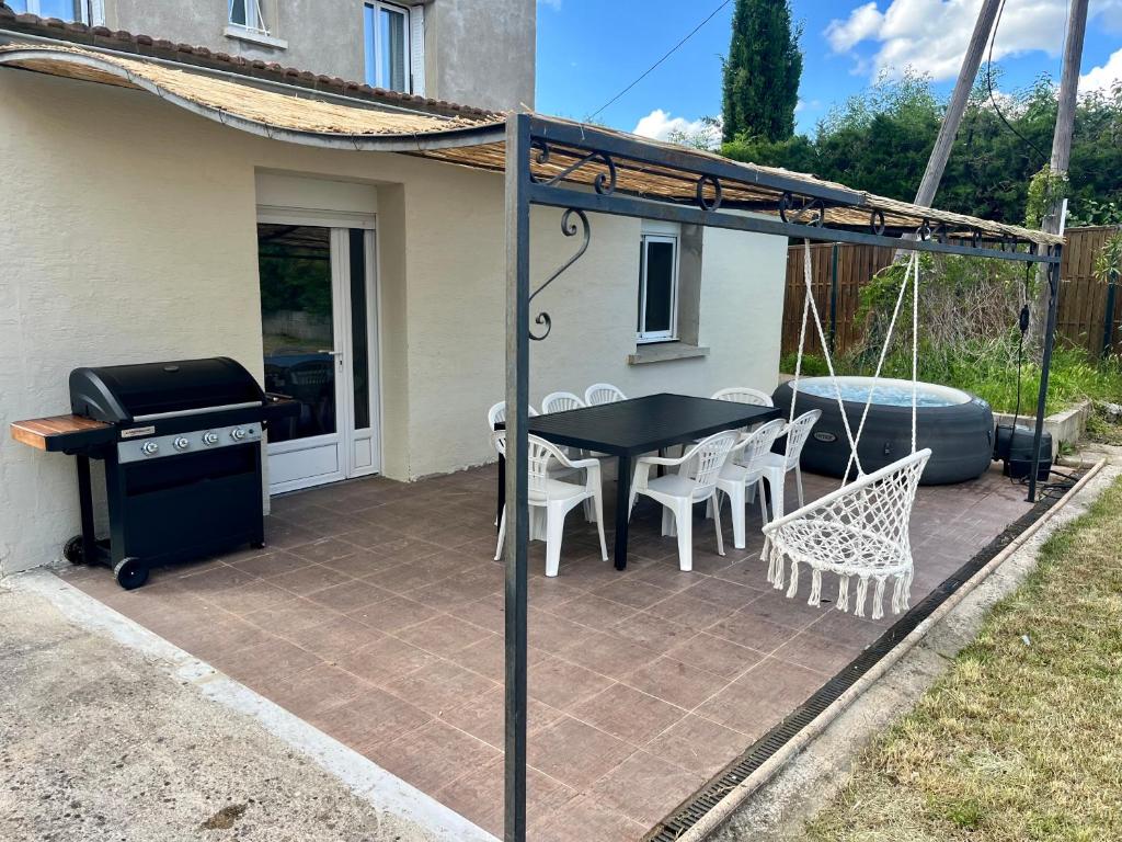 un patio avec une table, des chaises et un barbecue dans l'établissement Sky housse, à Alès