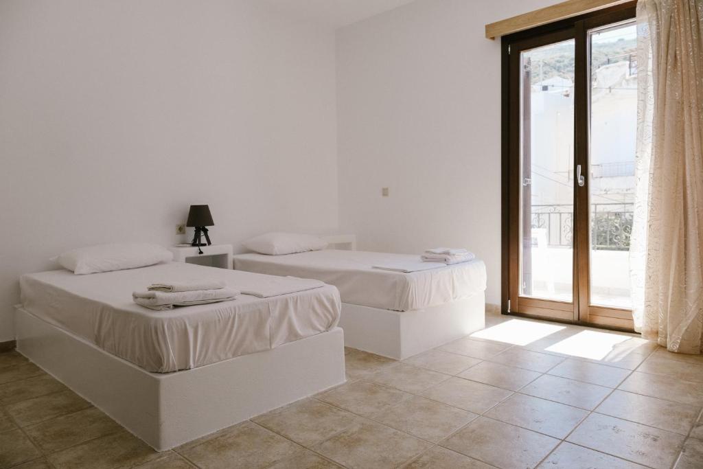 Duas camas num quarto branco com uma janela em Iliachtida apartments em Filótion