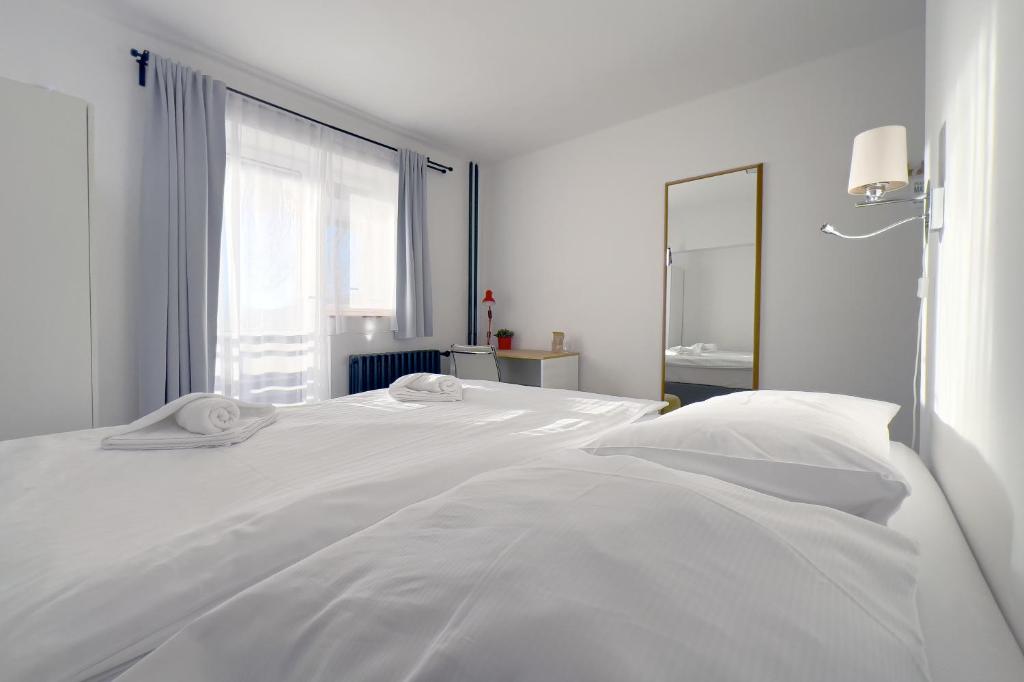 a white bedroom with a white bed and a window at Hotel Horní Pramen in Špindlerův Mlýn