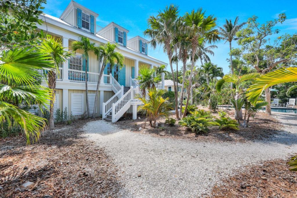 a large white house with palm trees in front of it at Roosevelt Cottage in Captiva