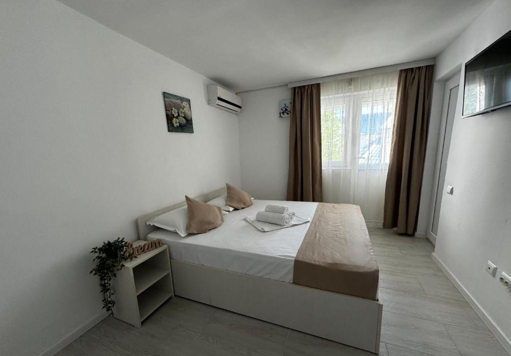 een witte slaapkamer met een bed en een raam bij Vila Yzabelle in Eforie Nord