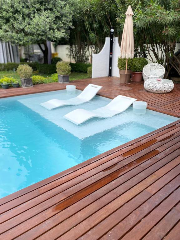une piscine avec une table et un parasol dans l'établissement Maison AdriAnna, à Vedène