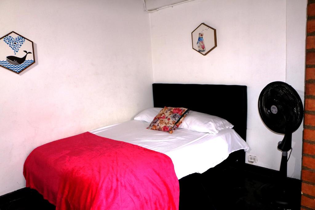 Schlafzimmer mit einem Bett mit einer roten Decke und einem Ventilator in der Unterkunft Aparta Suite Torre De Prado 301 in Medellín