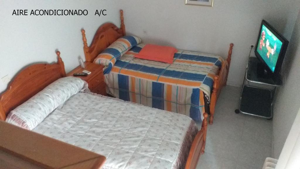 1 dormitorio con 2 camas y TV. en Habitacion Privada Doble en Toledo en Toledo