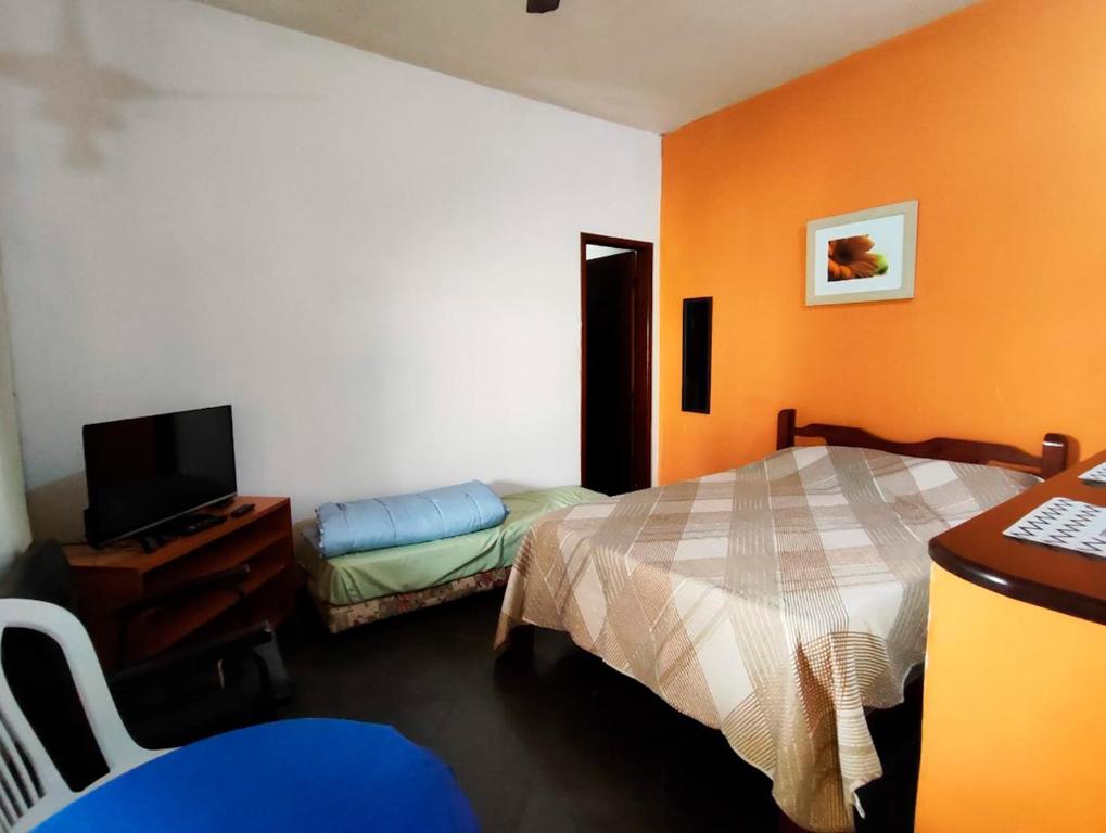 una camera da letto con pareti arancioni, un letto e una TV di Suites Americanas Em Jaconé a Jaconé