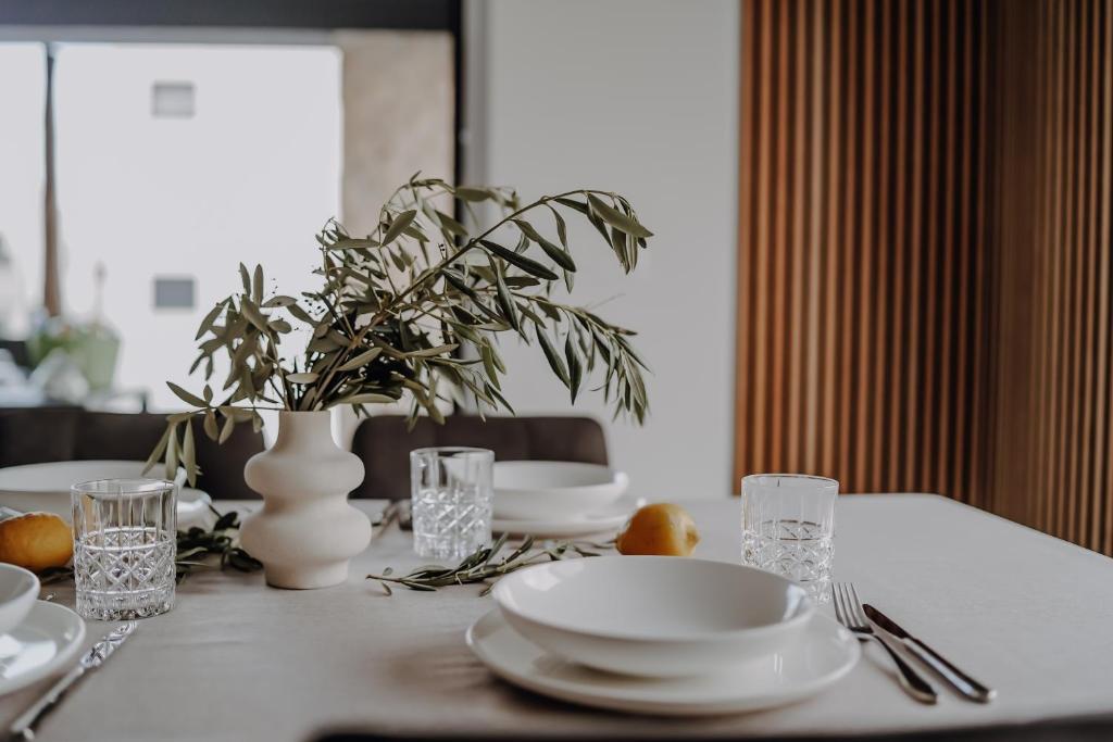 una mesa con platos y vasos y un jarrón en Lili Rose Mandre Luxury Apartments, en Mandre