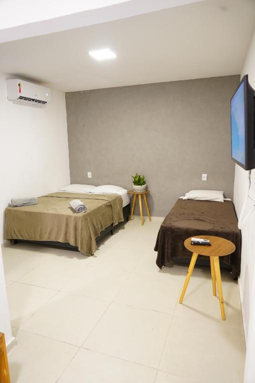 two beds in a room with a tv on a wall at Surf'O Hostel in Rio de Janeiro