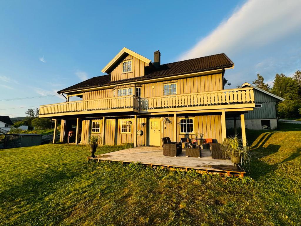 ein großes Holzhaus mit einer Terrasse davor in der Unterkunft Hjemmekoselig leilighet i underetasje 