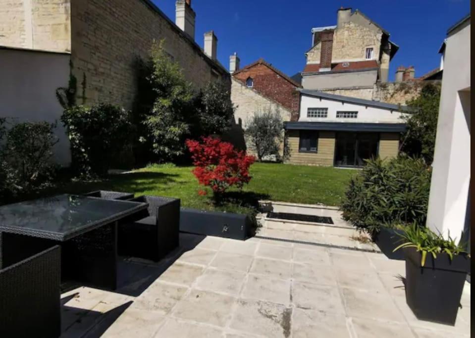 un jardin avec une terrasse et un bâtiment dans l'établissement Appartement charmant et élégant de centre ville, à Caen