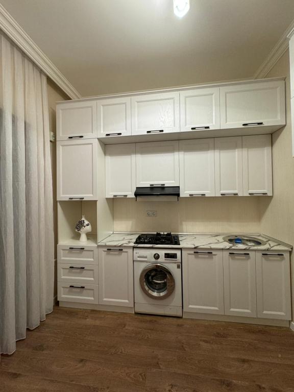 a kitchen with white cabinets and a washing machine at Bulvar Kristal apartment in Sumqayyt