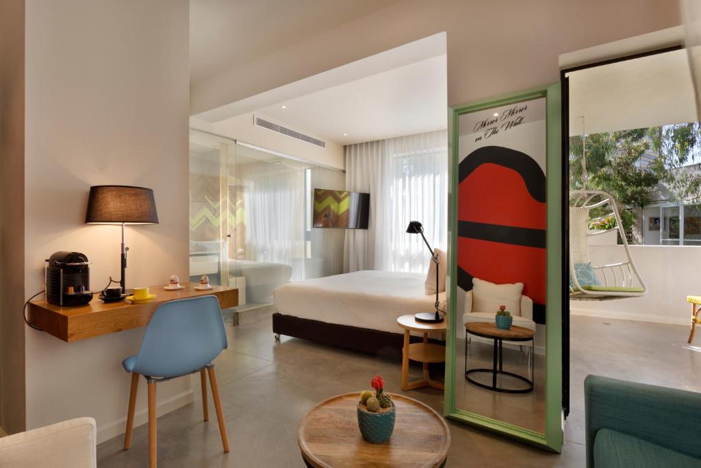 a hotel room with a bed and a table and chairs at Cucu Hotel By 7Minds in Tel Aviv